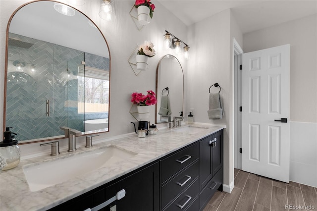 bathroom featuring a sink, a shower stall, double vanity, and wood tiled floor