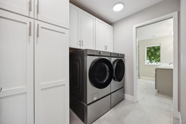 laundry area featuring washer and dryer, light tile patterned floors, and cabinets