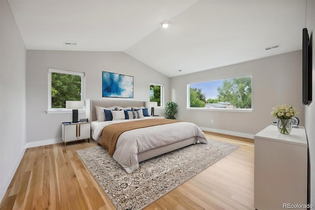 bedroom with multiple windows, light hardwood / wood-style floors, and vaulted ceiling