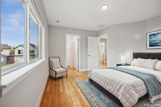 bedroom featuring ensuite bath and light hardwood / wood-style flooring