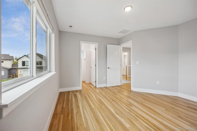 unfurnished bedroom with connected bathroom and light wood-type flooring