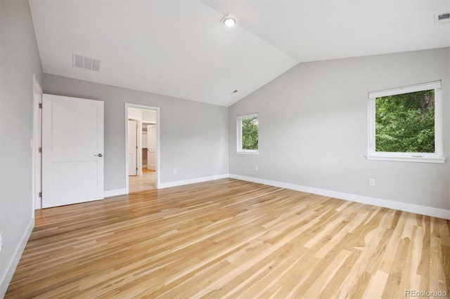 unfurnished bedroom with a walk in closet, lofted ceiling, and light wood-type flooring