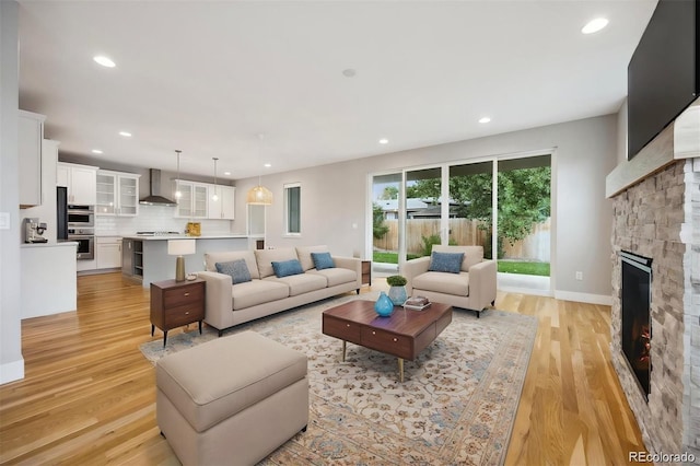 living room with light hardwood / wood-style flooring and a stone fireplace