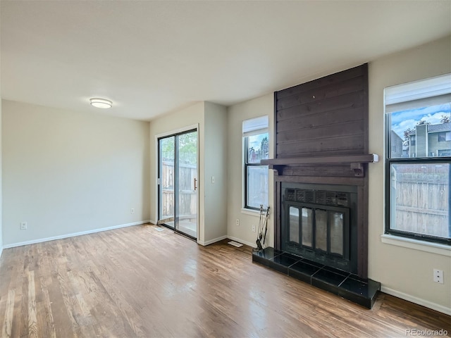 unfurnished living room with hardwood / wood-style floors and a tiled fireplace