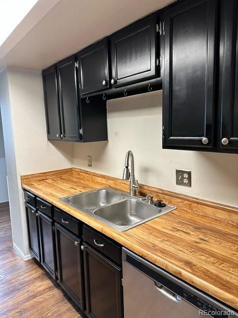 kitchen featuring stainless steel dishwasher, wooden counters, sink, and light hardwood / wood-style flooring