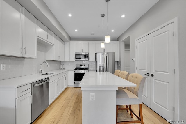 6211 W 28th Ct, Wheat Ridge, CO 80214 - kitchen featuring stainless steel appliances, a breakfast bar area, decorative backsplash, a kitchen island, and white cabinetry