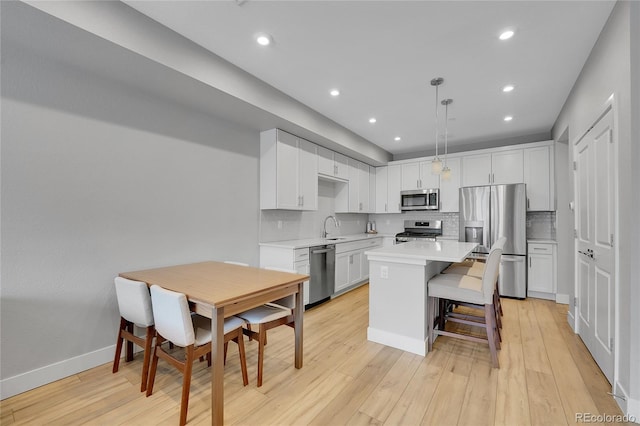 6211 W 28th Ct, Wheat Ridge, CO 80214 - kitchen featuring stainless steel appliances, light countertops, white cabinetry, tasteful backsplash, and a kitchen island