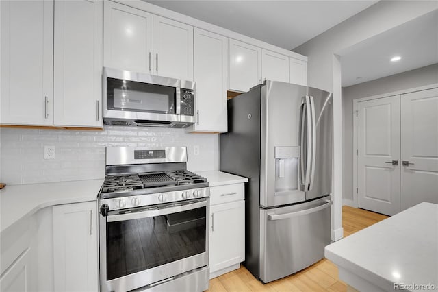 6211 W 28th Ct, Wheat Ridge, CO 80214 - kitchen featuring appliances with stainless steel finishes, light countertops, white cabinets, light wood-style floors, and recessed lighting