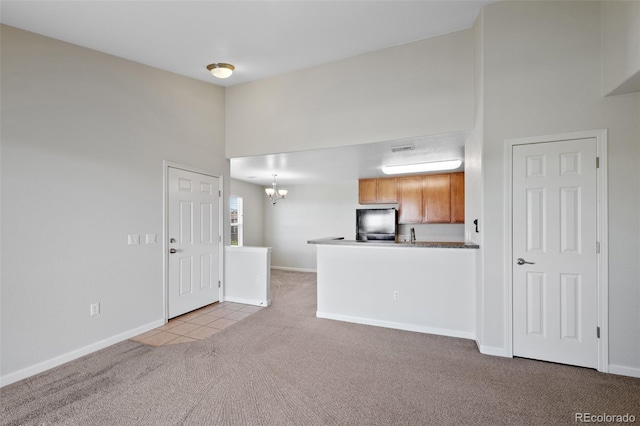 23451 E 5th Dr Unit 203, Aurora, CO 80018 - unfurnished living room featuring carpet floors, a high ceiling, a chandelier, baseboards, and tile patterned flooring