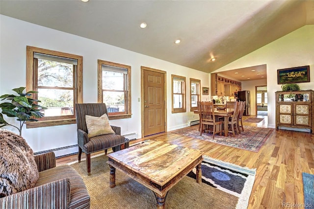 587 21 1/8 Rd, Grand Junction, CO 81507 - living room with a baseboard radiator, light wood finished floors, vaulted ceiling, and a wealth of natural light