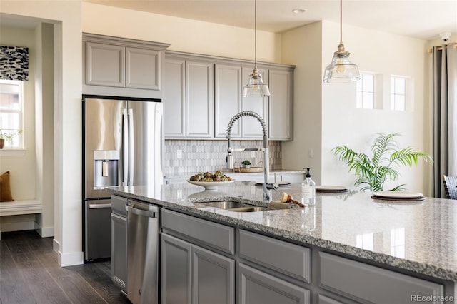 kitchen featuring appliances with stainless steel finishes, gray cabinetry, sink, pendant lighting, and dark hardwood / wood-style floors