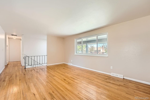 empty room featuring visible vents, light wood-style flooring, and baseboards