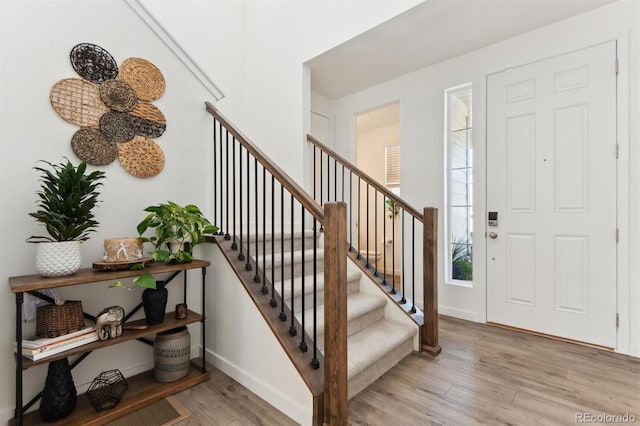 foyer entrance with light wood-type flooring, stairway, and baseboards