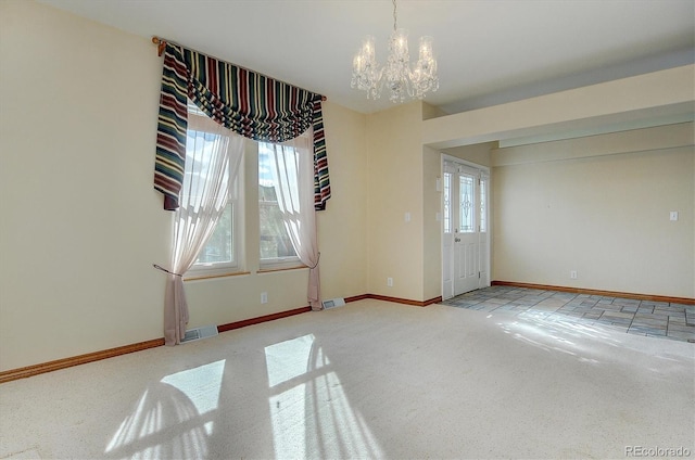 empty room with light colored carpet and a chandelier