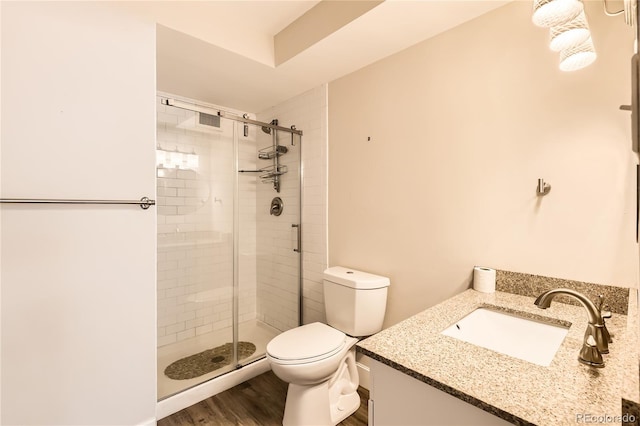 bathroom featuring toilet, a stall shower, wood finished floors, and vanity