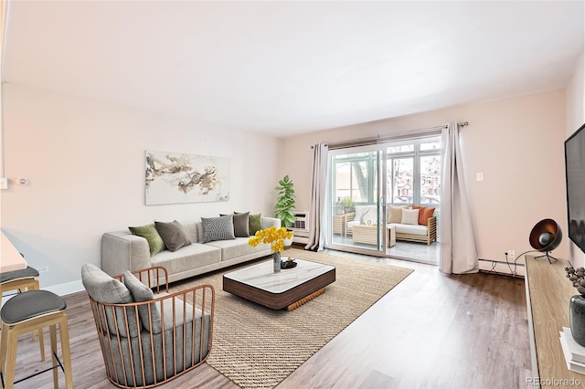 living area with baseboard heating, wood finished floors, and baseboards