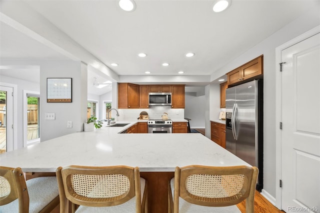 5991 S Eudora Way, Centennial, CO 80121 - kitchen with appliances with stainless steel finishes, light countertops, brown cabinets, recessed lighting, and a peninsula