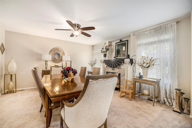 dining room featuring a high end fireplace, light colored carpet, and ceiling fan