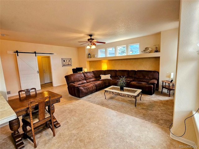 living room featuring a textured ceiling, a barn door, carpet floors, and ceiling fan