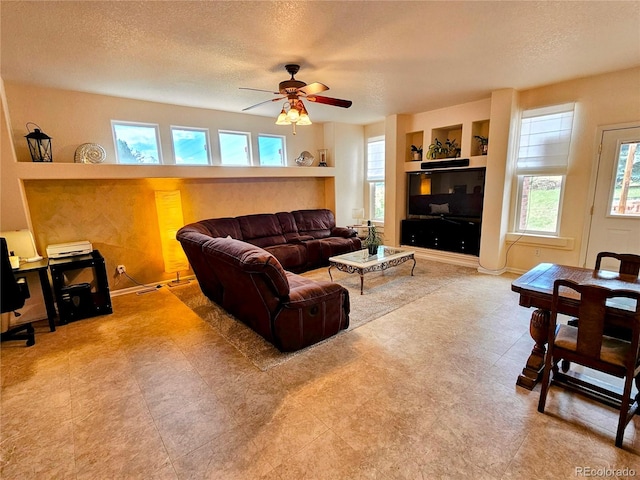 living room featuring built in shelves, a textured ceiling, and ceiling fan