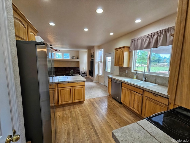 kitchen featuring ceiling fan, stainless steel appliances, light hardwood / wood-style flooring, and plenty of natural light