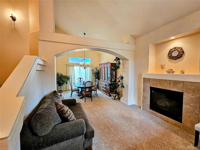 living room featuring a tiled fireplace, carpet flooring, and an inviting chandelier