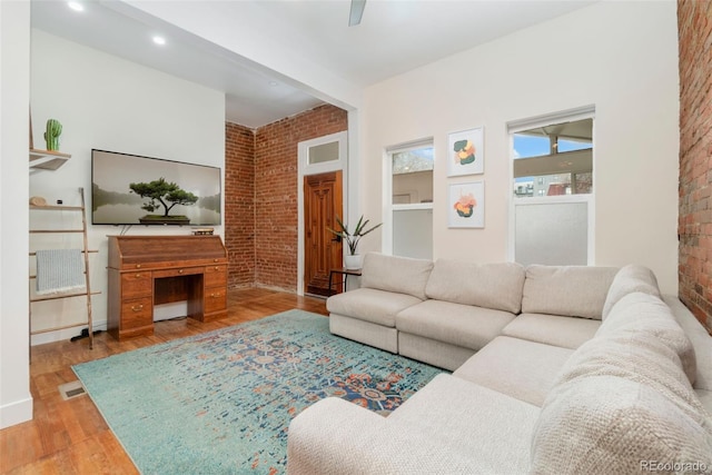 living area featuring brick wall and wood finished floors