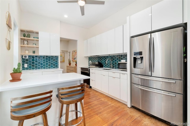 kitchen featuring light countertops, backsplash, appliances with stainless steel finishes, a sink, and modern cabinets