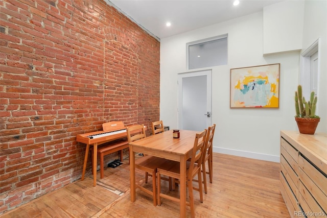 dining room with recessed lighting, baseboards, light wood-style flooring, and brick wall