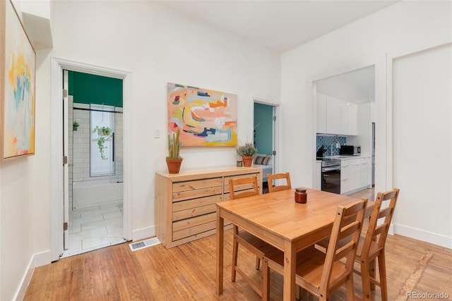 dining space with light wood finished floors, baseboards, and visible vents