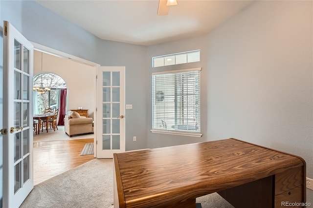 carpeted office featuring ceiling fan with notable chandelier and french doors