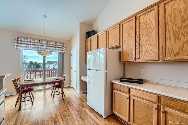 kitchen featuring white refrigerator, decorative light fixtures, and light hardwood / wood-style floors