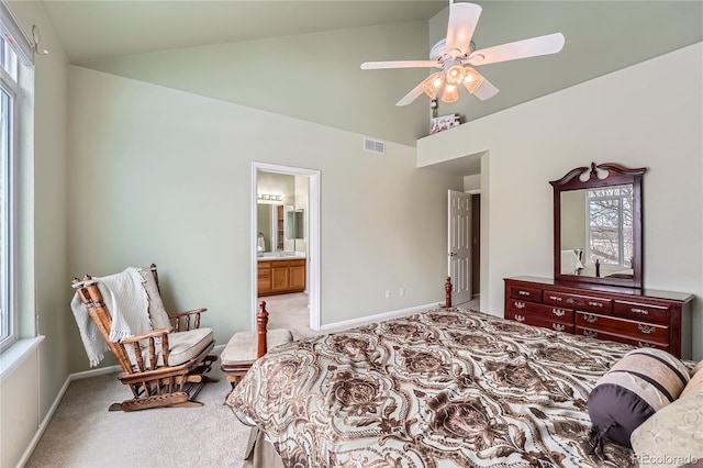 bedroom with ceiling fan, light colored carpet, ensuite bathroom, and high vaulted ceiling