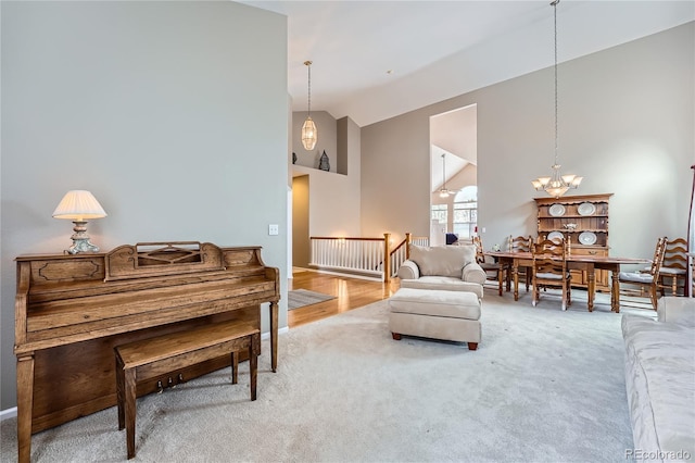 living room with a notable chandelier, high vaulted ceiling, and carpet floors