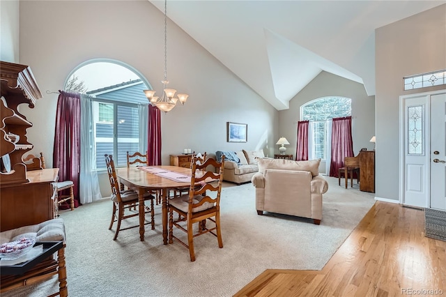 dining space with high vaulted ceiling, light wood-type flooring, and a chandelier