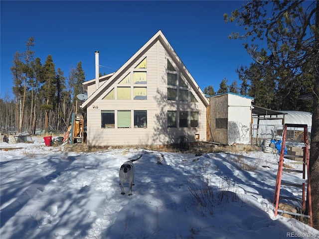 snow covered rear of property featuring a carport