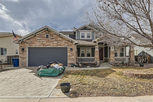 craftsman-style house featuring an attached garage, concrete driveway, stone siding, and roof mounted solar panels