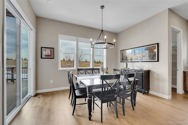 dining room with light wood-style floors, a chandelier, and baseboards