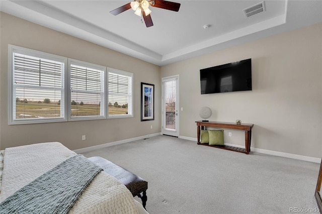 carpeted bedroom featuring baseboards, a tray ceiling, access to exterior, and a ceiling fan
