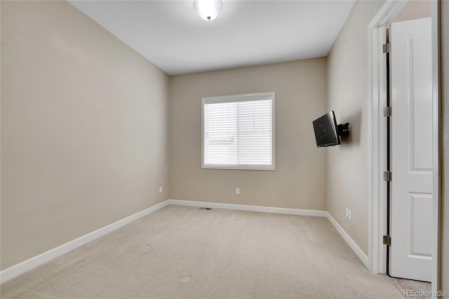 spare room with baseboards and light colored carpet