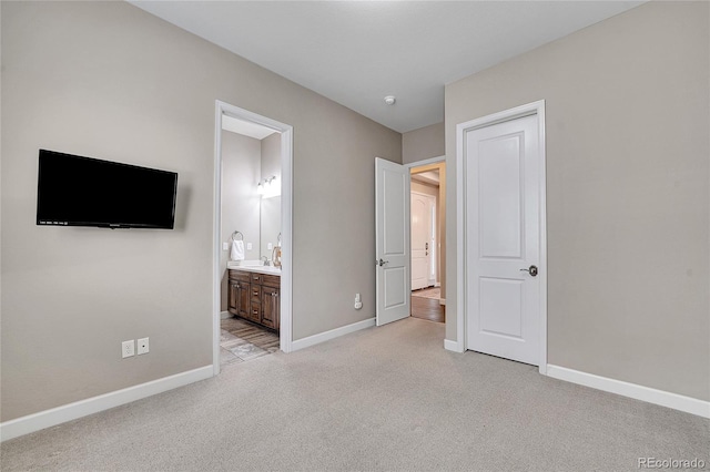 unfurnished bedroom featuring light colored carpet, baseboards, and ensuite bath