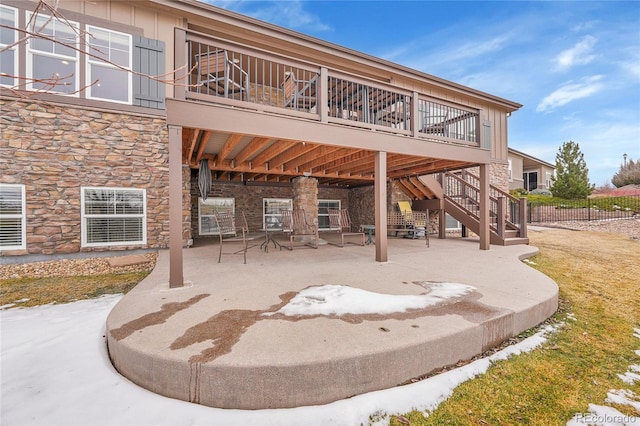 rear view of property featuring stone siding, a patio area, fence, a deck, and stairway