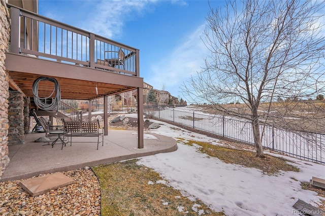 yard layered in snow with a patio, fence, and a deck