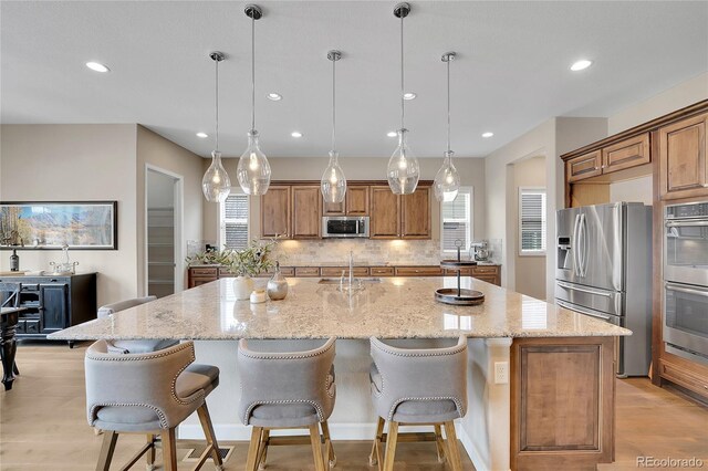 27615 E Moraine Dr, Aurora, CO 80016 - kitchen featuring appliances with stainless steel finishes, light wood-style floors, a sink, brown cabinetry, and recessed lighting
