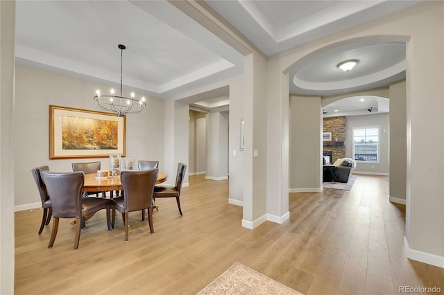 27615 E Moraine Dr, Aurora, CO 80016 - dining space with a raised ceiling, arched walkways, a chandelier, light wood-type flooring, and baseboards