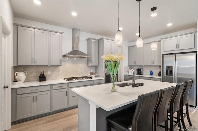 23936 E River Front Dr, Aurora, CO 80019 - kitchen with wall chimney range hood, appliances with stainless steel finishes, gray cabinetry, tasteful backsplash, and a kitchen breakfast bar