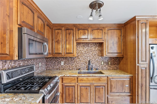 1196 N Grant St Unit 106, Denver, CO 80203 - kitchen with appliances with stainless steel finishes, brown cabinets, light stone countertops, and decorative backsplash
