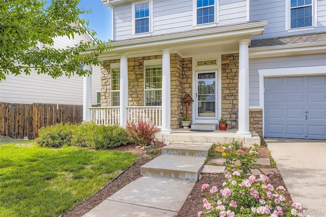 15649 E 7th Cir, Aurora, CO 80011 - doorway to property featuring a porch, stone siding, and a garage