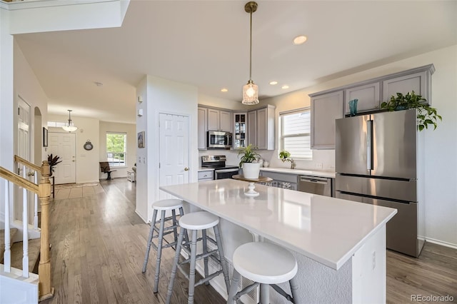 15649 E 7th Cir, Aurora, CO 80011 - kitchen featuring stainless steel appliances, gray cabinets, wood finished floors, a breakfast bar area, and light countertops