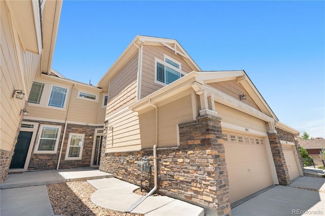 14892 E Poundstone Dr, Aurora, CO 80015 - view of side of property with a garage, stone siding, and concrete driveway